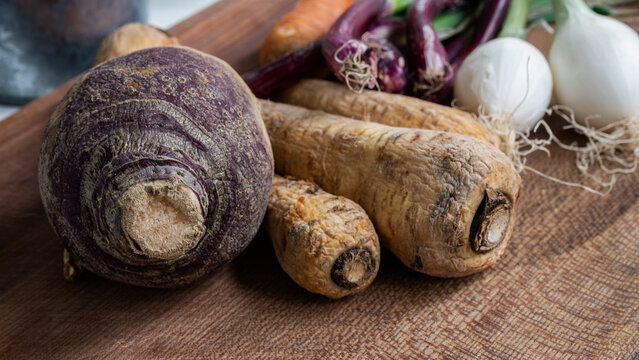Seasonally grown vegetables (carrots, onions, parsnips,rutabaga, parsnip) displayed on a wooden surface.  Soup ingredients and food preparation concept. 