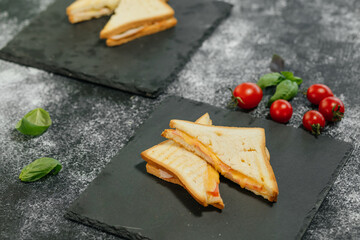 There are two slices of sandwich on the grey napkin on the table.