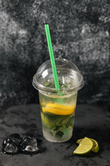 There is a lemonade which is made of fresh fruits on the black napkin on the table.