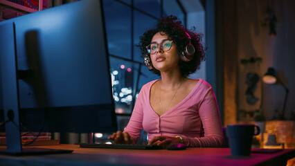 Attractive Multiethnic Latin Woman in Headphones Using Computer in Stylish Loft Apartment in the...
