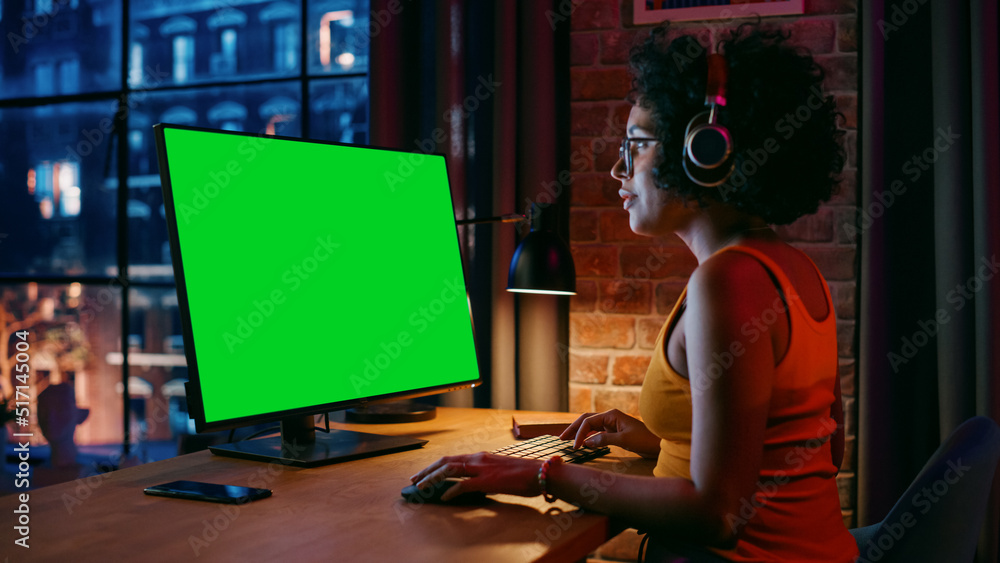 Aufkleber young beautiful female in headphones working from home on desktop computer with green screen mock up