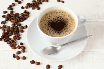 Cup of coffee with heart pattern and coffee beans on white wooden table Top view