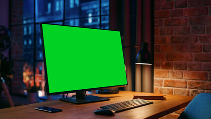Desktop Computer Monitor Standing on a Table with a Green Screen Chromakey Mock Up Display. Cozy...