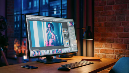 Naklejka premium Modern Loft Office with Night City View From Big Window. Computer Monitor with Opened Editing Softwear Standing on The Work Desk of the Designer. New Type Business Employee Left For Lunch.