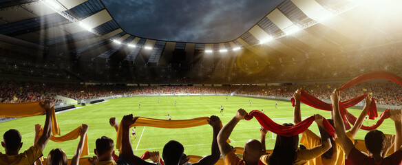 Back view of football, soccer fans cheering their team with colorful scarfs at crowded stadium at...