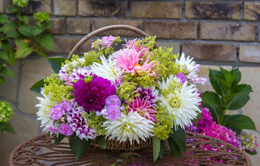 Bouquet of dahlias in a basket on a garden table