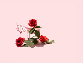 Open bird cage, red roses, green leaves, floral arrangement, pastel pink background. Minimal freedom concept. 