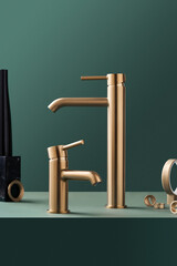  Two modern gilded chrome faucets on the background of the emerald wall. Bathroom interior concept.