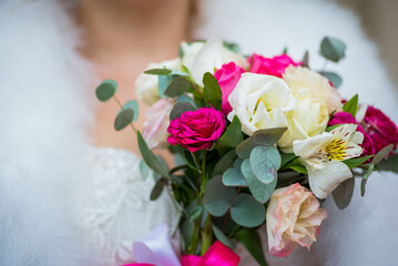 a bouquet of flowers on the background of a bride in a white dress. Wedding ceremony