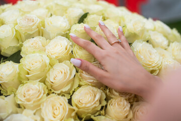 Obraz na płótnie Canvas bride's hand with a ring on a large bouquet of white roses