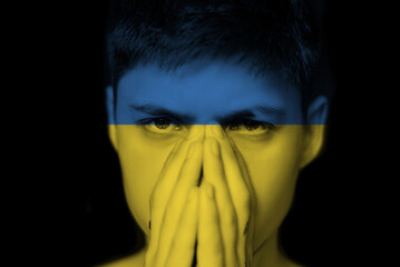 a young man prays for Ukraine. Portrait on a black background