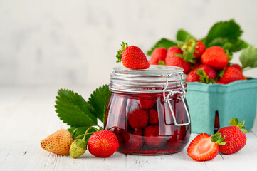 Strawberry jam with whole berries on a white wooden table. Selective focus. Copy space