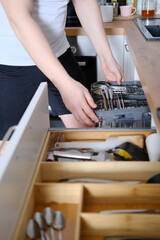 A man takes out clean cutlery from the dishwasher
