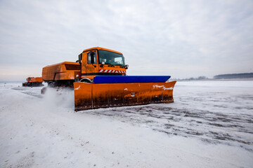 Snowplow truck cleans runway on airfield during snowfall