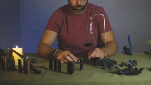a man doing shotgun cartridges reloading with gun primers, shells, gunpowder, cartridges, scales on the table