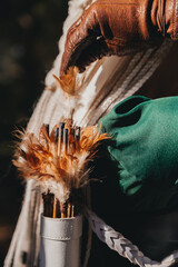 Quiver with arrows and feathers. Woman in a medieval green dress with white dreadlocks from the...