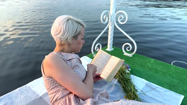 A girl on a raft eats a berry and reads a book