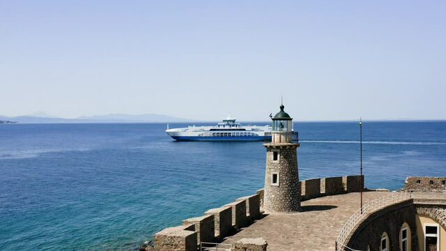 Aerial drone shot of Antirrio fortress with lighthouse and ferry boat passing by on background.