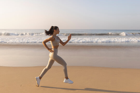 Running woman. Female runner jogging during outdoor workout on beach. Beautiful fit fitness model outdoors. High quality photo
