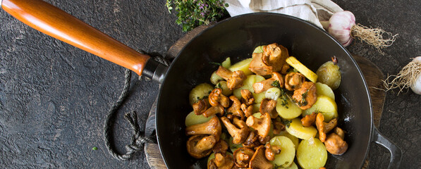 frying pan with fried potatoes with chanterelles on the table