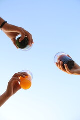 Friends toasting, cheers glasss of juice toasted, bottom view, open sky summer photography concept