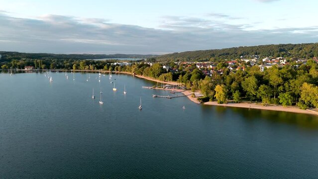 Aerial view flying drone of town Herrsching at Ammersee lake, luxurious residential area with high class marina and beautiful view. Lakeside sailing harbor near munich in Germany, recreation area