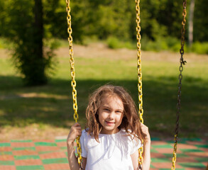 summer portrait of a little girl swinging on a swing.