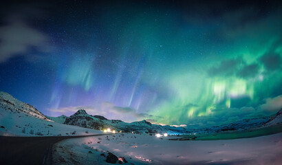 Beautiful Aurora borealis, Northern lights glowing over snow mountain and coastline in the night sky at Lofoten Islands