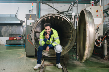 Naklejka na ściany i meble Caucasian engineer man in safety uniform sitting and reporting on processing large duct contrainer in industry manufacturing factory