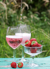 Two glasses of rose sparkling wine and strawberry on a  table. Romantic picnic outdoors. Close up photo of glass tableware. Summer drinks and food. 