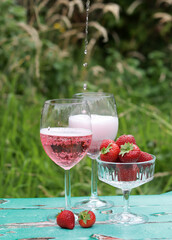 Two glasses of rose sparkling wine and strawberry on a  table. Romantic picnic outdoors. Close up photo of glass tableware. Summer drinks and food. 