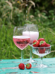 Two glasses of rose sparkling wine and strawberry on a  table. Romantic picnic outdoors. Close up photo of glass tableware. Summer drinks and food. 