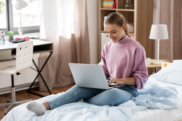 children, education and learning concept - happy smiling student girl with laptop computer at home