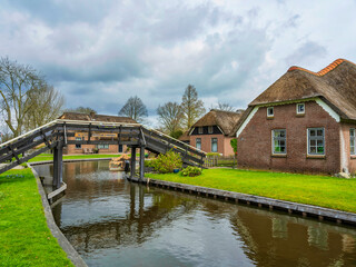 Fototapeta na wymiar Charming village of Giethoorn, Dutch houses and wodden bridge with lush gardens on the canal, Netherlands