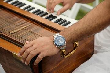 hands of Indian man playing the harmonium at an event outdoors