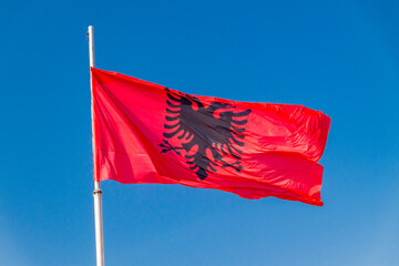 National flag of Albania waving on blue sky.