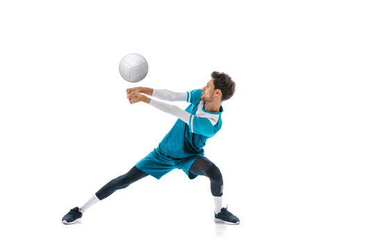 Portrait of young man, volleyball player in motion, training, playing isolated over white studio background