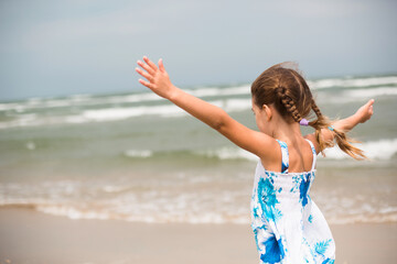 Portrait of a girl on the seashore. The child enjoys the waves, relaxing on the beach, traveling.