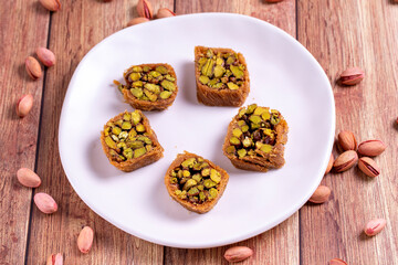 Pistachio kadayif dessert. Kadayif baklava with pistachio filling on a wooden floor. Turkish cuisine desserts. Close-up. local name fıstıklı kadayif