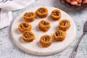 Bulbul Kadayif with Pistachio. Kadayif baklava with pistachio filling on a stone floor. Turkish cuisine desserts. Close-up. local name Antep Fıstıklı Bülbül Kadayıf