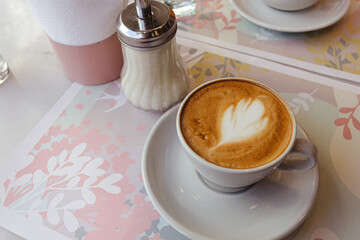 Taza de café negro con espuma y leche en mesa de bar
