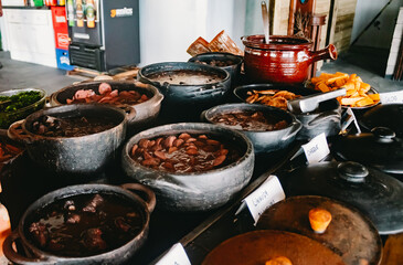 Various types of Feijoadas being prepared in traditional wood stove in Brazilian restaurant