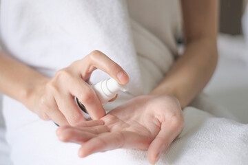 Asia woman sitting on bed and applying cream on Hand.