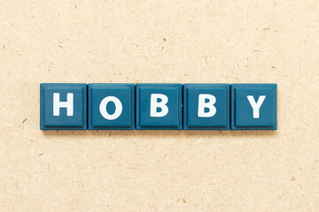 Tile alphabet letter in word hobby on wood background - obrazy, fototapety, plakaty
