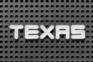White alphabet letter in word texas on black pegboard background