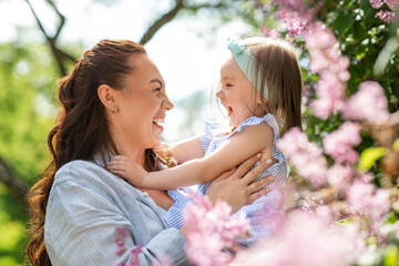 Naklejka premium family, motherhood and people concept - happy mother with little daughter at summer park or garden