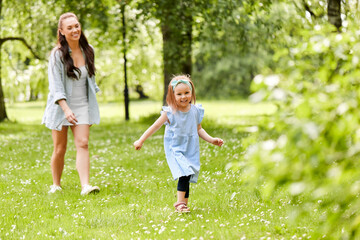 family, motherhood and people concept - happy mother with little daughter playing at summer park