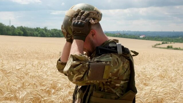 A Ukrainian soldier in motion, walking through a wheat field, dressed in camouflage and a helmet with weapons in his hands, looking ahead. The military enjoys nature. The Concept of War and Peace
