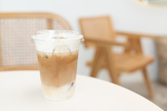 Fresh coffee, iced cappuccino, Macchiato, latte with separate milk and coffee. Coffee in a plastic cup on a wooden table. plastic iced coffee mug on wooden table