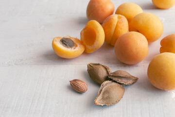 Apricots and kernel on white wooden background. Apricot seeds.